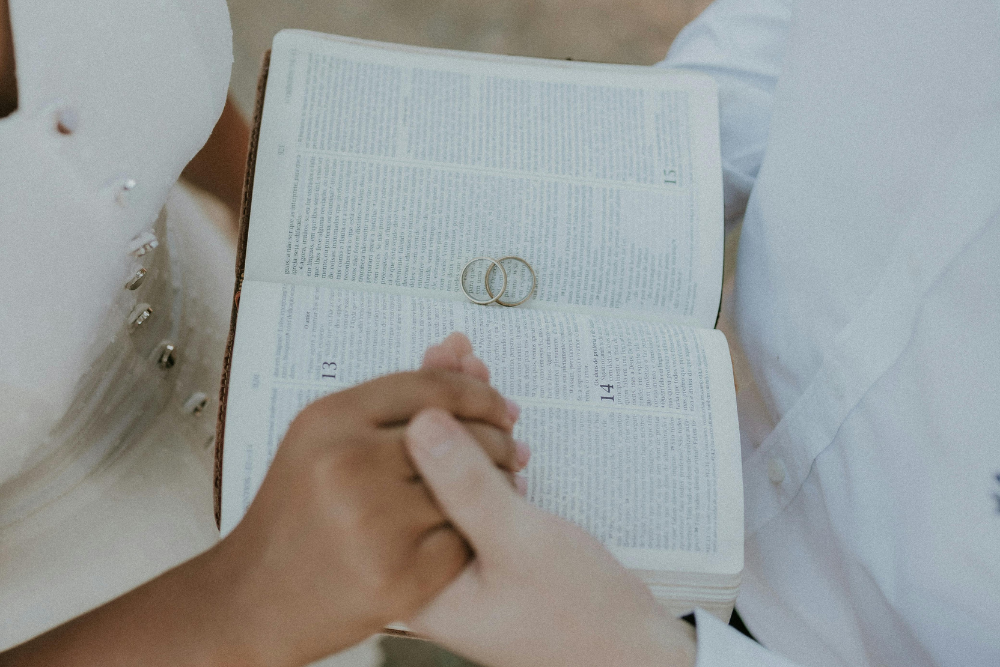 Noivos segurando Bíblia com alianças na cerimônia de casamento cristão